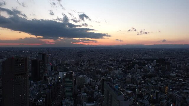 TOKYO, JAPAN : Aerial high angle sunset CITYSCAPE of TOKYO. View of dramatic clouds and buildings around Shibuya. Japanese city life and metropolis concept. Long time lapse zoom in shot dusk to night.