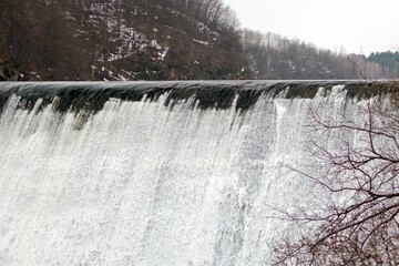 blurred motion of spring stormy streams of falling water from the height of dam