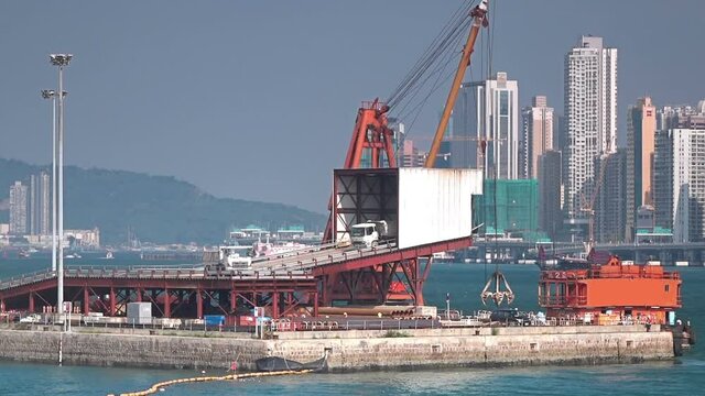 Truck unloading sands and gravel in the construction barge, Victoria Harbor.