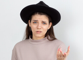 Portrait of a confused frustrated girl pointing away and looking at camera isolated over white background