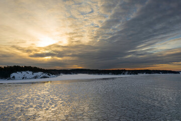 Sunset. Beautiful view of the northern snow covered shores of Scandinavia, Baltic sea at sunset time in winter. Amazing sky bright colors and clouds on the horizon. Winter landscape. 