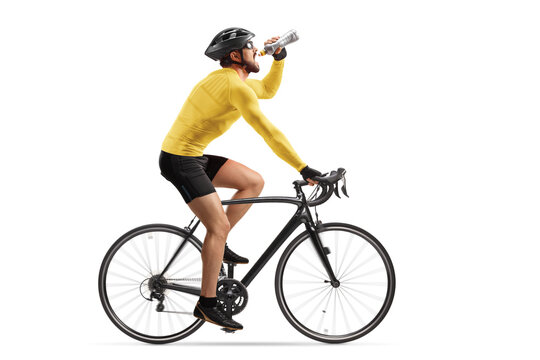 Profile shot of a male athlete riding a bike and drinking from a bottle