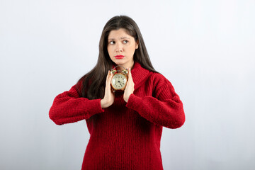 Young beautiful brunette woman holding an alarm clock standing
