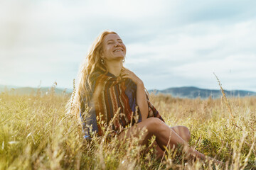 Beautiful slender strong legs peek out from under striped cape on the shoulders of a girl sitting...