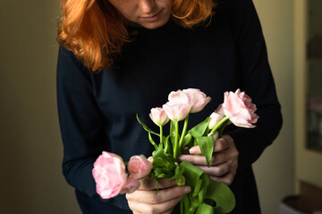 A pregnant woman holds in her hands a beautiful bouquet of fresh spring flowers, pink tulips. Retro style, vintage, woman grounding, conscious life, slowing down, harmony.