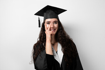 Surprised bachelor girl in graduation robe and cap on white background. Happy and funny young woman smile. Student achieve master degree in univesity