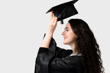 Surprised bachelor girl in graduation robe and cap on white background. Distance learning online. Study at home. Graduation from college.