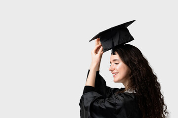 Surprised bachelor girl in graduation robe and cap on white background. Distance learning online. Study at home. Graduation from college.