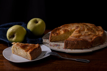A slice of homemade apple pie. Background: yellow apple and blue napkin.