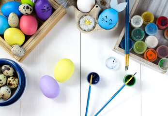 Easter colored eggs, paints and paint brushes are on a wooden table. The concept of preparing for the Easter holiday.