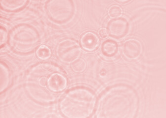Pink shadow texture of the sun light refraction in concentric circular waves from drops falling on water. Cool nature background of clear transparent water. Unobtrusive rainy weather pattern.