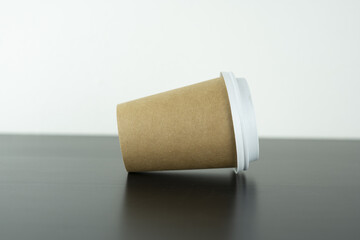 a takeaway paper cup beside it on a wooden table.