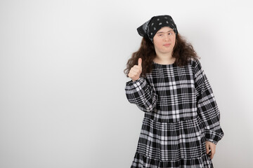 Image of a young cute girl with down syndrome standing and showing a thumb up