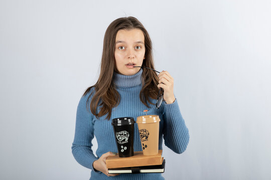 Image of a young girl model holding books and two cups of coffee