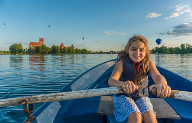 Cute little girl rowing oars in a boat on the Galve lake in Trakai, Lithuania