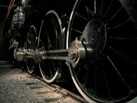Close up steam locomotive wheels, connecting rods, and coupling rods at night on tracks and ballast nobody