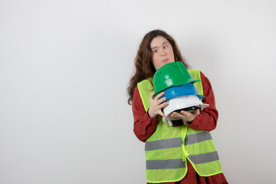 Image of a young cute girl with down syndrome standing in vest and holding crash helmets