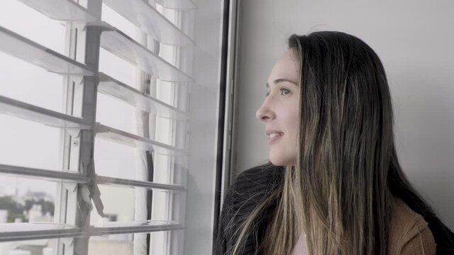 Woman Looking Out The Window Shutters Smiling Closing And Opening Window Glass And Shutters. Beautiful Lady  In Morning Looking Out The Blinds To The Street. Closing Shutters Close Up. Positive Happy