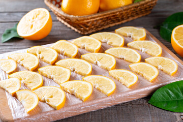 Frozen lemon slices on a cutting board on a wooden table