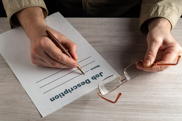 Filling out the job description in a working environment on the desktop. Close up of man hands...