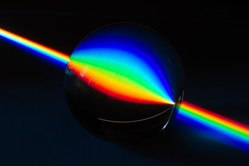 A Rainbow streak of light traveling in the darkness and being inverted by the reflection on a glass...