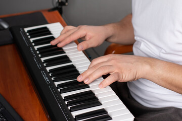 Man plays on the keyboard of the synthesizer. Online education