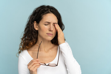 Sleepy young caucasian woman holding glasses rubbing eyes, feels tired after working on computer,...