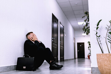 Fototapeta na wymiar An unemployed businessman sits alone in the corridor of an offic