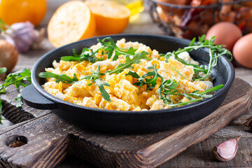 Scrumble eggs with corn, cream cheese sauce, herbs and vegetable served in cast iron skillet.