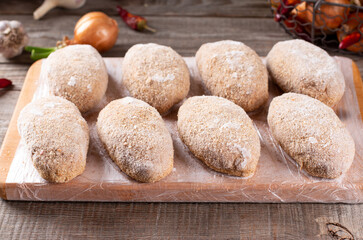 Frozen cutlets lie on a wooden board. Raw meat semi-finished products