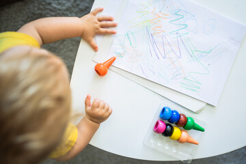 a child painting on a sheet on a table at home The child has colored paints and is learning with the montessori method