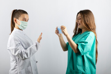 Female doctor in white uniform looking at a nurse in green uniform