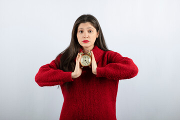 Young beautiful brunette woman holding an alarm clock standing