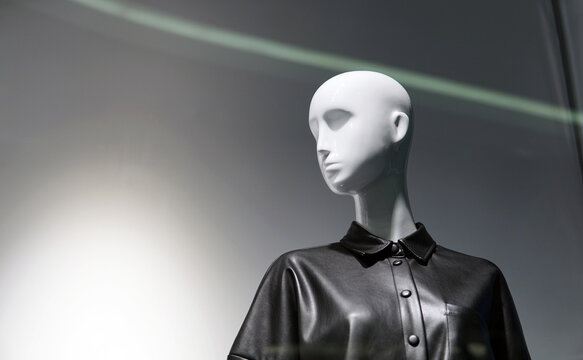 Female mannequin in the window of a fashionable clothing store. Minimalism and contrasting lighting, free space for an inscription. In the turn of the head, hidden emotions can be seen.
