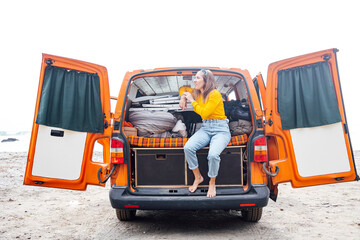 Woman on vacation with her orange van on the beach © karrastock