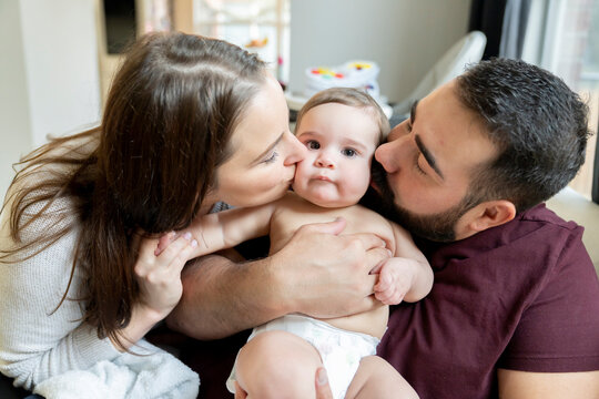 Man and woman kissing baby on cheeks