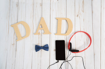 Father's day concept surrounded by headphones, mobile phone, Bow tie and space for text on white background.