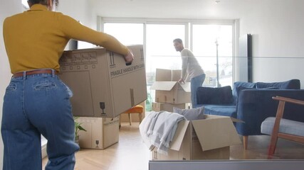 Portrait of loving young mixed ethnicity couple sitting on floor in lounge of new home hugging as they unpack removal boxes together