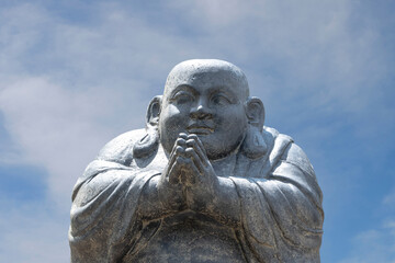 Happy Buddha figure, at sunset before the blue sky