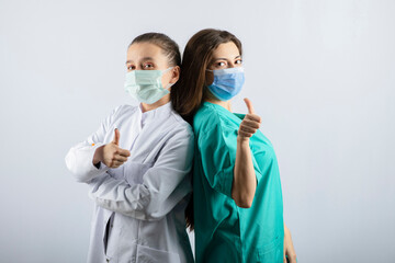 Female doctors in medical masks showing thumbs up