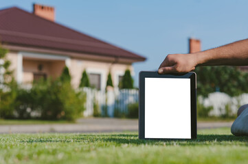 Tablet in hand, on the lawn against the backdrop of the house.
