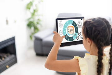 little girl using tablet with home remote control , living room in background, smart home