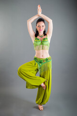 young brunette woman in green belly dance costume smiles at camera in studio