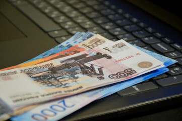 a bundle of Russian bank money, of various denominations, lies on a computer keyboard