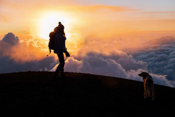 Climber with her dog on top of the Acatenango volcano in Guatemala enjoying the sunset-woman hiking...