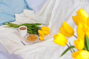 Obraz na płótnie Canvas A bouquet of fresh yellow tulips and breakfast with coffee and homemade marmalade. Breakfast in bed. Spring flowers. The concept of spring and holiday, March 8, International Women's Day,