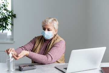Elderly woman sanitizing her hands with alcohol gel