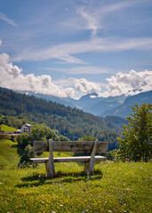 Panoramic view of a beautiful landscape in the Swiss Alps with beautiful flowers. Bench in the foreground