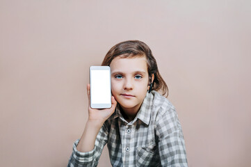 A teenager holds a smartphone in his hand on a light background. Mockup