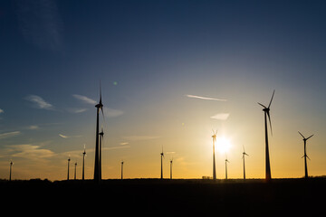 viele Windräder bei Sonnenuntergang stehen auf einem Feld und produzieren Strom	